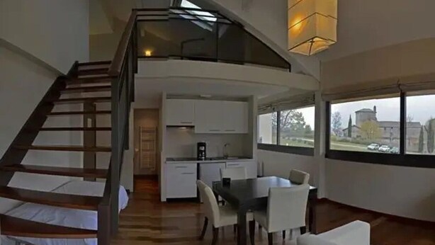 A modern loft-style apartment with a loft bedroom, a kitchen, and a dining area. - ZEcamping 3 étoiles pet friendly locatif TV clim 48m2 6 pers (Saint-Lizier)