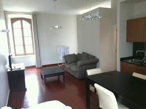 A compact living space with a dining area, a sofa, a small table, and a kitchenette. - ZEcamping 3 étoiles pet friendly locatif TV clim 48m2 6 pers (Saint-Lizier)