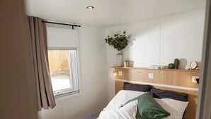 Une chambre à coucher avec un lit, une table de chevet, une plante et une fenêtre avec des rideaux.