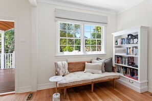 A room with a wooden bench, a bookshelf, and a window with a view of trees.