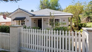 A single-story house with a white picket fence, a front porch, and a garage.