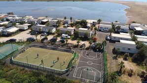 Ein Campingplatz mit Mobilheimen, einem Basketballplatz und einem Strand im Hintergrund.