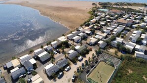Une zone côtière avec accès à la plage, des mobil-homes et un terrain de sport.