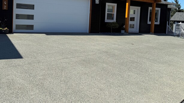 Ein zweistöckiges Haus mit Garage, einer kleinen Veranda und einer Auffahrt.