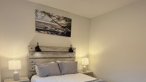 Ein Schlafzimmer mit einem Bett, zwei Nachttischen, einem Wandbild und einem Holz-Kopfteil.