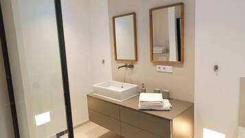 Une salle de bain moderne avec un grand lavabo, deux miroirs et un meuble-lavabo doté de tiroirs.