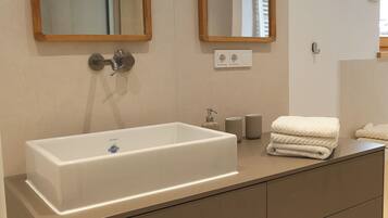 Un bagno moderno con un ampio lavabo rettangolare, due specchi fissati alla parete e un mobile contenitore con cassetti.