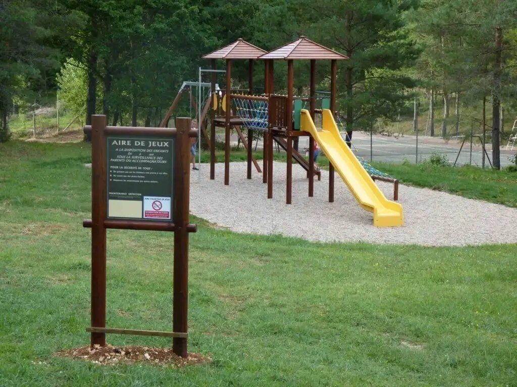Un'area giochi con uno scivolo giallo e strutture per arrampicarsi, immersa nel verde.