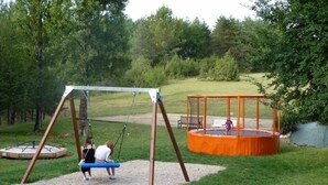 A playground with a swing set and a trampoline. - ZEcamping 3* pataugeoire piscine locatif TV 31m2 5 pers (Pezuls)