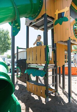 Une structure de jeux pour enfants comprenant un toboggan, des éléments d’escalade et une plateforme.