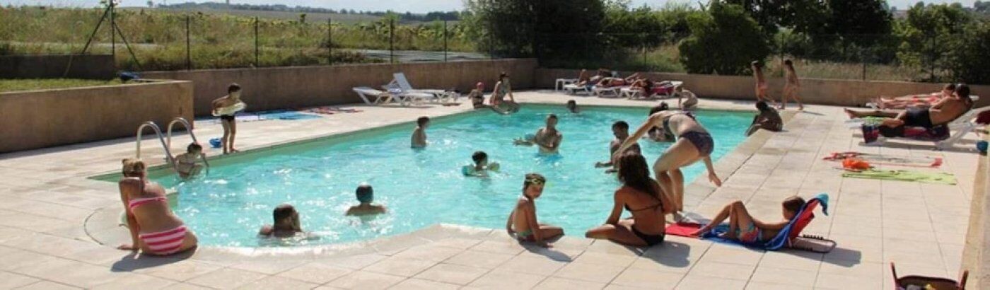 A swimming pool area with multiple people swimming and lounging.