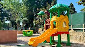 Ein Spielplatz mit einer gelben Rutsche und einer grünen Kletterkonstruktion.