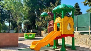 A playground with a yellow slide and a green climbing structure.