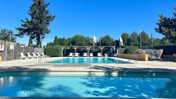 A swimming pool with lounge chairs, a wooden deck, and a flagpole.