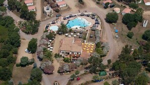 An aerial view of a resort with multiple buildings, a central swimming pool, and surrounding greenery. - ZEcamping 3* piscine 1km plage locatif 25m2 5 pers (Viggianello)