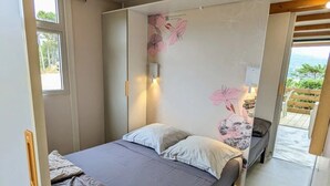 Une chambre à coucher avec un lit, une table de chevet, une lampe fixée au mur et une fenêtre.