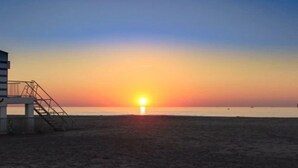 Una playa con una torre de salvavidas y una puesta de sol al fondo.