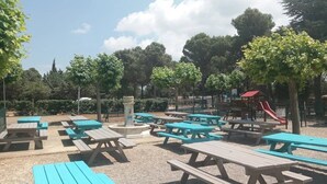 Un espace extérieur aménagé avec des tables de pique-nique et une aire de jeux.