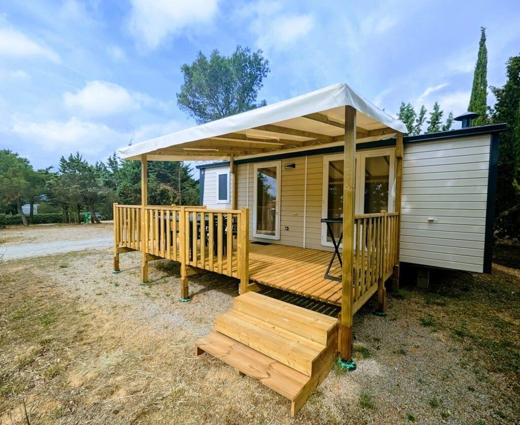 A wooden deck with a covered area and a small attached building.