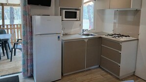 Cocina compacta con refrigerador, microondas, pileta y estufa.