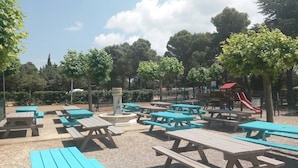 Un espacio al aire libre con mesas de picnic y un parque infantil.