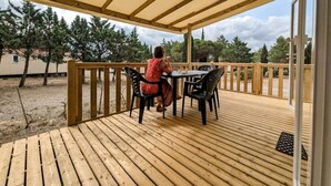 A covered outdoor patio with a wooden deck, a table, and chairs.