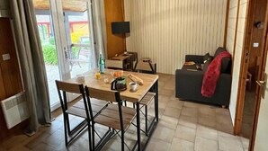 Una habitación acogedora con una mesa de comedor, sillas, un sofá y un televisor.