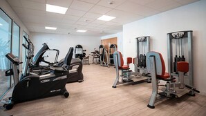 Kuntosali, jossa on kuntopyörät ja muut kardiolaitteet, painonnostovälineet ja puulattia.