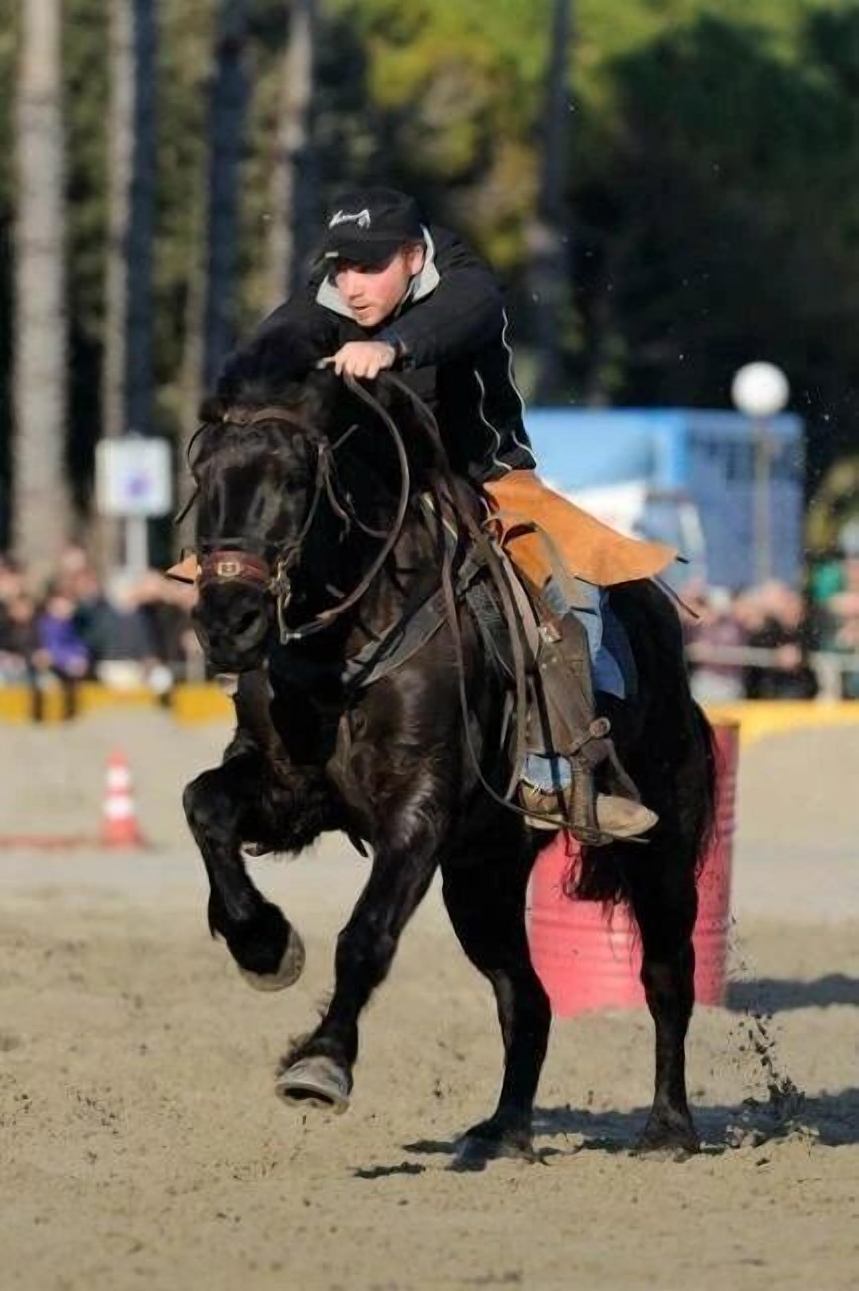 Una persona montando a caballo en una arena al aire libre.