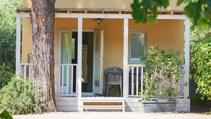 Een gelijkvloers huis met een veranda, een bankje en een bloempot.