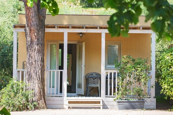 Une maison de plain-pied avec un porche, un banc et un pot de fleurs.
