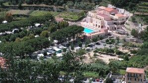 Luchtbeeld van een resort met een centraal gebouw, een zwembad en omliggend groen.