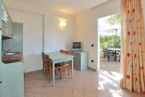 Une pièce de taille modeste comprenant une table à manger, des chaises, un téléviseur et un coin cuisine.