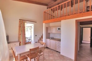 A spacious kitchen with a dining area, wooden staircase, and a view of the outdoors.