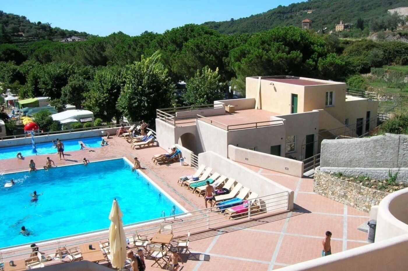 A swimming pool with multiple lanes, sun loungers, and a small building with a red roof.