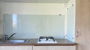 Ett kök med ljusa träskåp, en diskho i rostfritt stål och en gasspis.