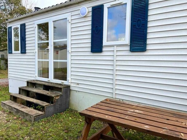 Ett litet hus i ett våningsplan med en veranda och en träbänk.