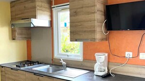 Una cocina moderna con armarios de madera, estufa integrada, un lavaplatos y una cafetera.