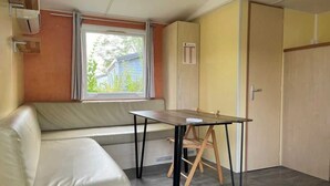 Una habitación compacta con sofá, una mesita, ventana con cortinas y una puerta.
