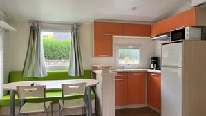 Une cuisine compacte comprenant un coin repas, un réfrigérateur et un four à micro-ondes.