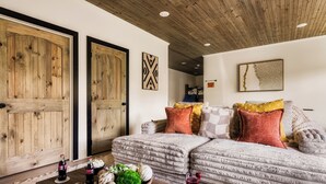 A cozy living room with a sofa, a coffee table with snacks and drinks, and a wooden ceiling.