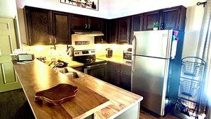 A modern kitchen with dark wooden cabinets, a stainless steel refrigerator, and a wooden countertop. - 3B/2BA Cabin-Style Condo in Pinetop Lakes. Steps from Golf, 30 Mins to Sunrise! (Pinetop Country Club)