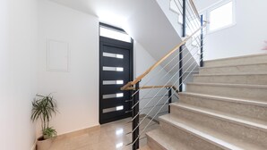 A modern staircase with a wooden handrail and metal balusters, leading to a landing with a potted plant. - Amazing apartment in Podstrana with WiFi (Podstrana)
