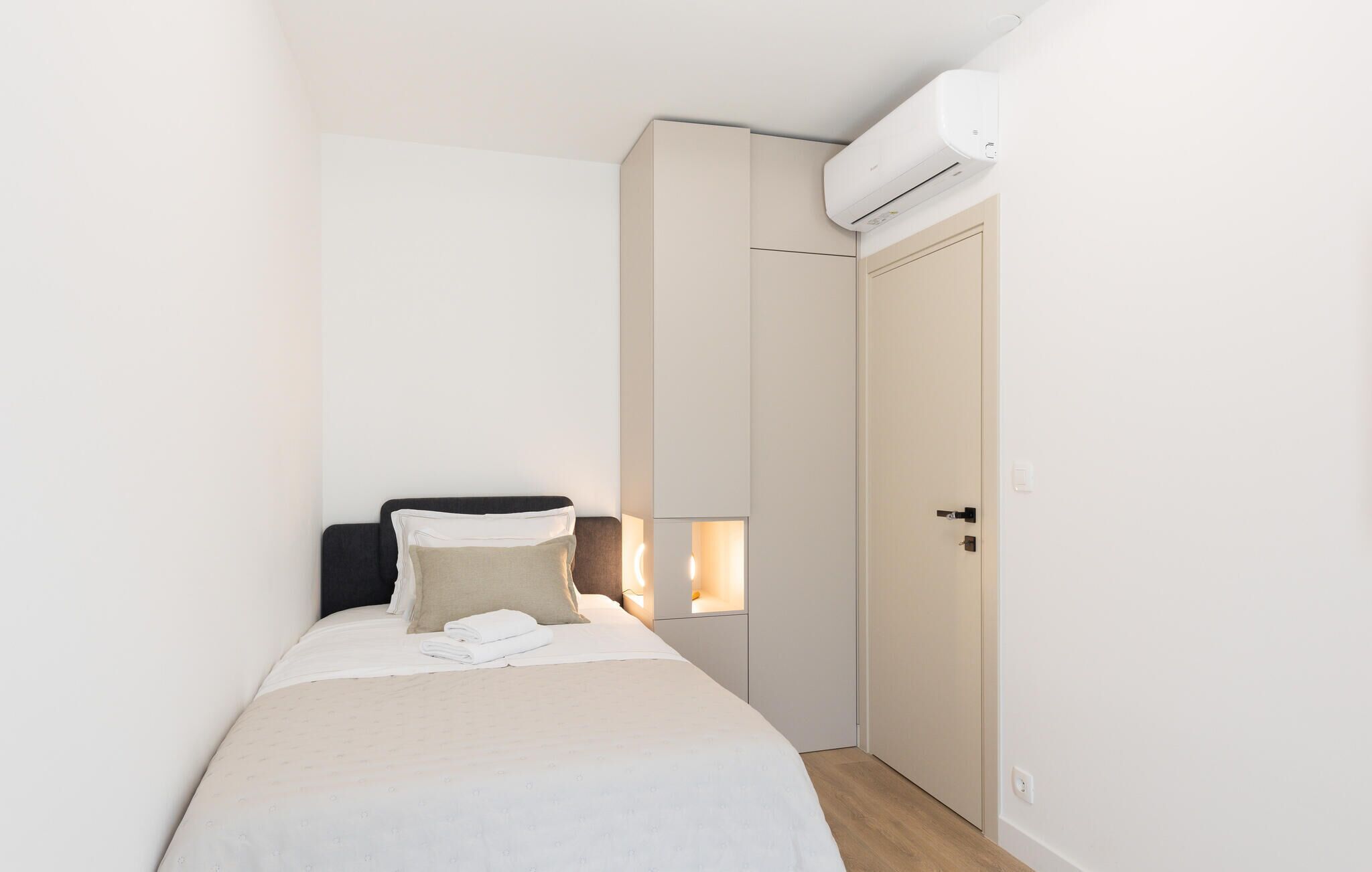 A small, neatly arranged bedroom with a bed, bedside tables, and a wardrobe.