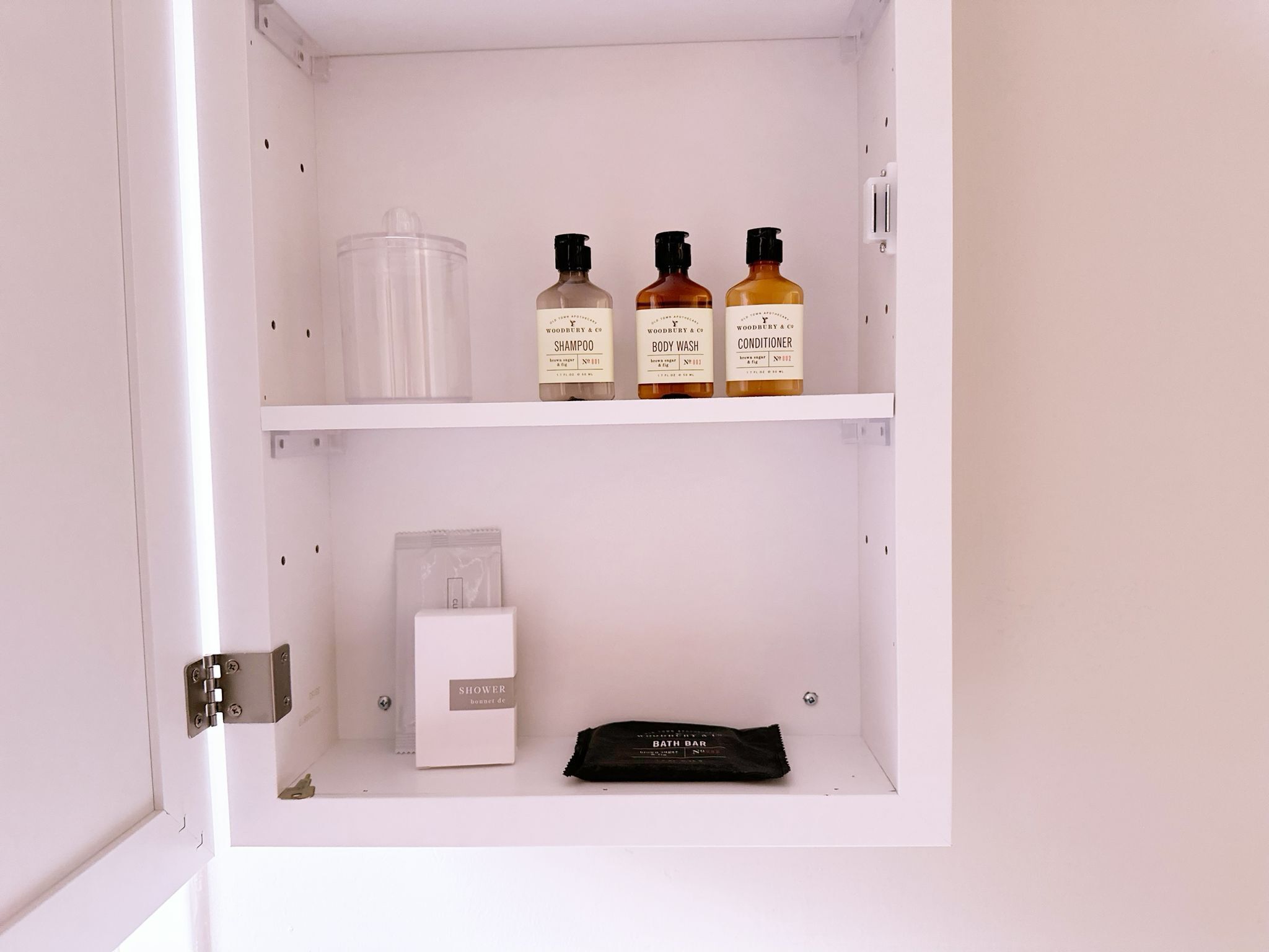 Un mueble de baño con artículos de aseo, incluyendo una barra de ducha, champú, gel de baño y acondicionador.