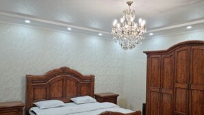 A bedroom with a wooden bed, nightstands, a wardrobe, and a chandelier.