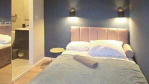 Ein Schlafzimmer mit einem großen Bett, einem Nachttisch, einem kleinen runden Tisch und einem Spiegel.