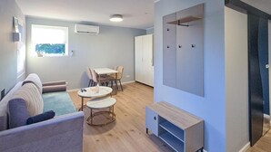 Ein modernes Wohnzimmer mit einer Couch, zwei kleinen Tischen, einer TV-Konsole und einem Kleiderschrank.