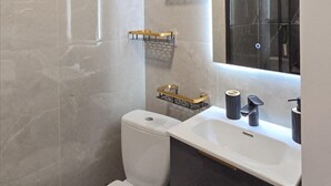 Ein modernes Badezimmer mit einer weißen Toilette, einem Waschbecken mit schwarzem Wasserhahn und einem Handtuchhalter mit goldenem Halter.