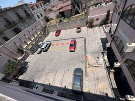 Vista aérea de un estacionamiento con varios autos estacionados, rodeado de edificios con balcones y ventanas.